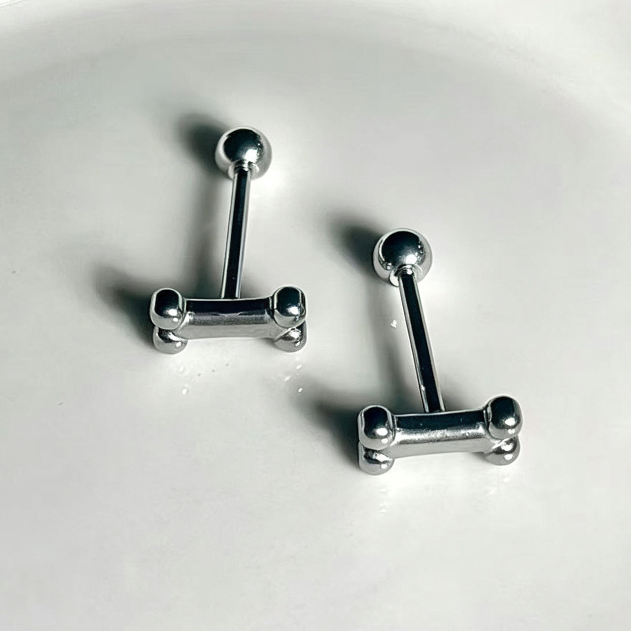 Two 1.6mm 316 stainless steel dog bone tongue barbell piercings displayed on white background