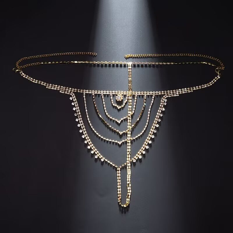 Flat lay product shot of gold rhinestone thong waist chain with crystal dangles and extension clasp on dark background.