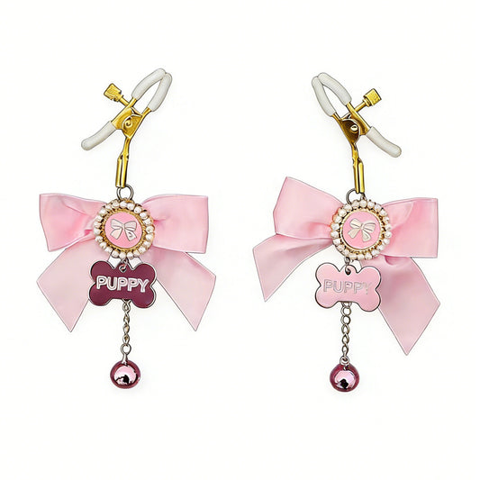 Adjustable gold-toned nipple clamps with white protective soft tips and pink bow charms.