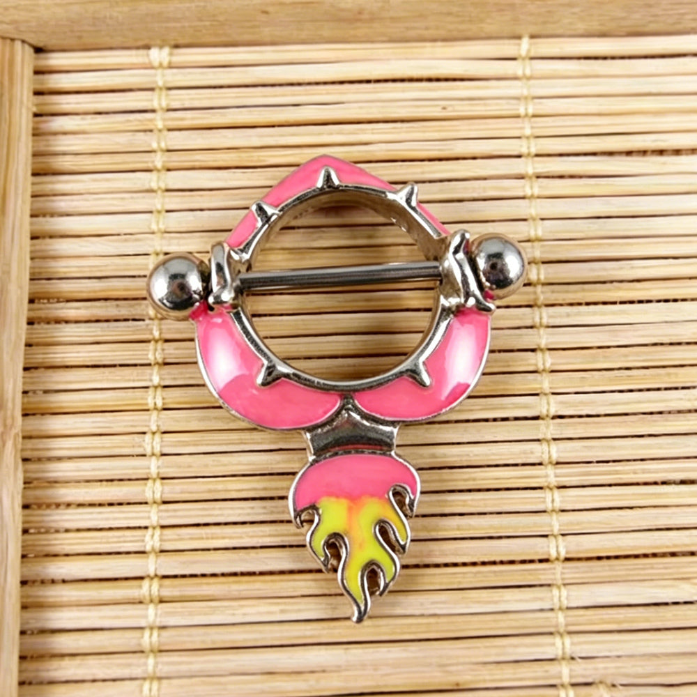 Close-up real shot of a pink enamel flame heart nipple ring shield on a textured bamboo background highlighting details.