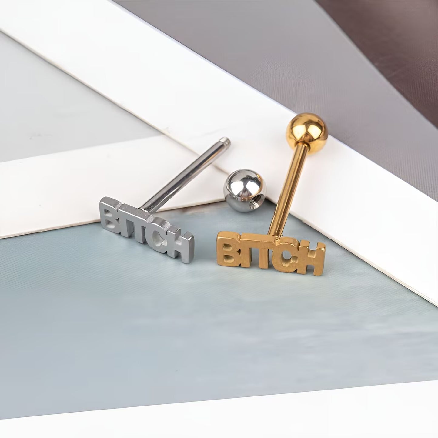 Gold and silver letter tongue rings showing unscrewed 5mm threaded ball closure mechanism.