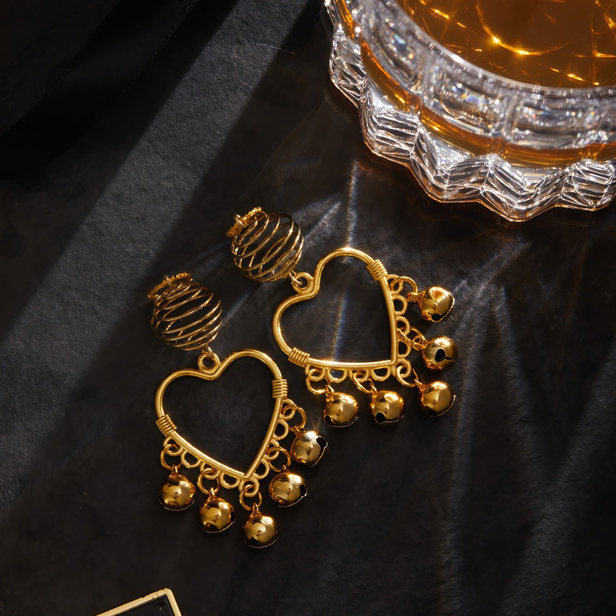 Romantic filigree heart nipple dangles with bells in a lifestyle product photography setting.