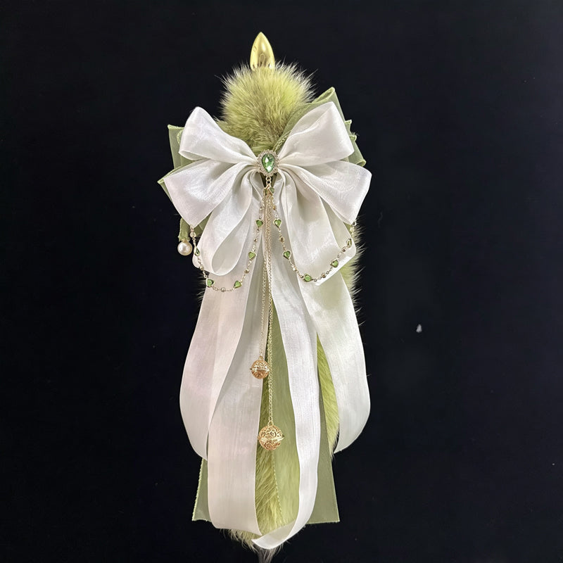 Decorative faux fur tail plug featuring layered ribbons, dangling gold bells, and crystal center