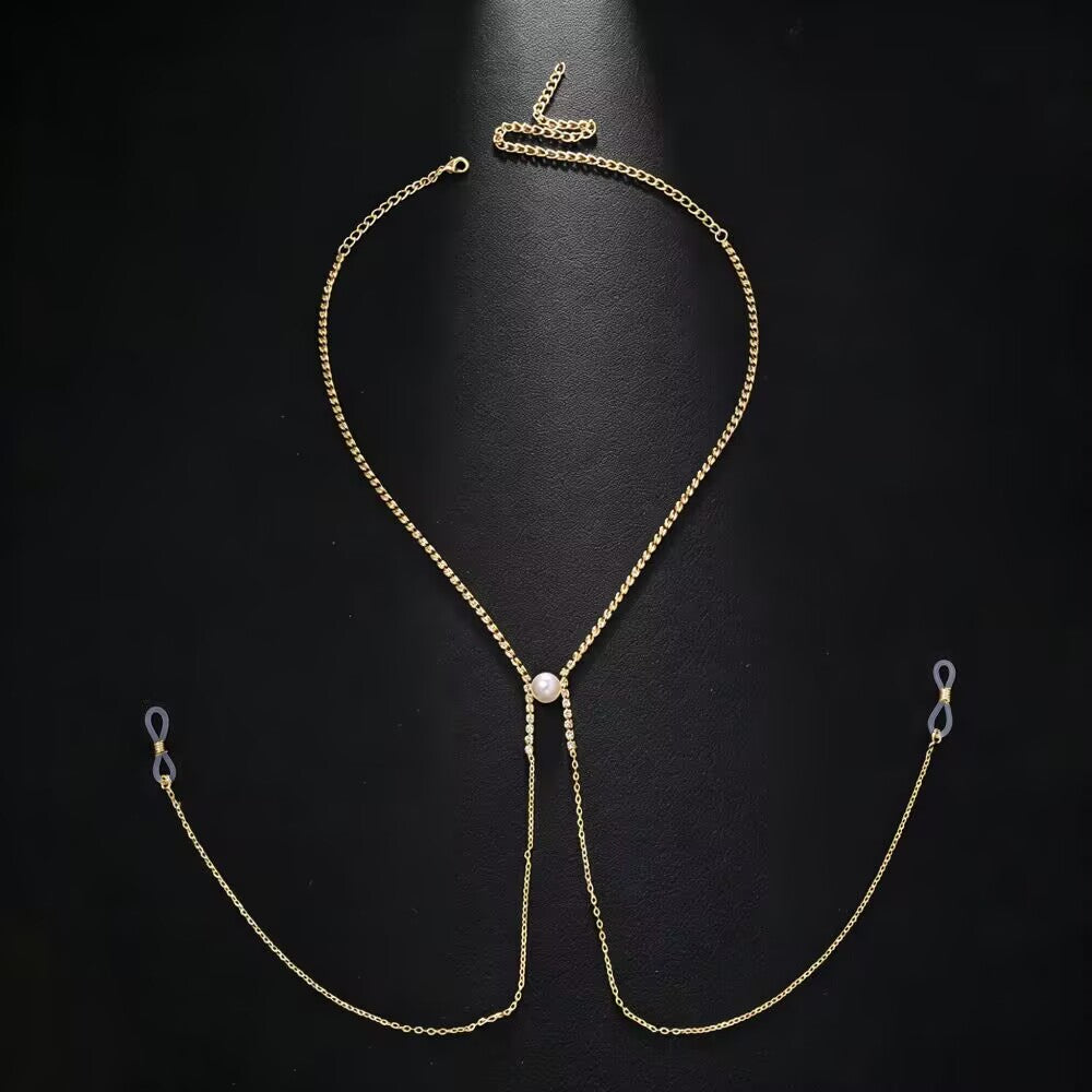 Flat lay product shot of a gold-plated adjustable fake nipple ring body chain with an integrated necklace, crystal rhinestones, a faux pearl, and clear silicone loops on a black background.