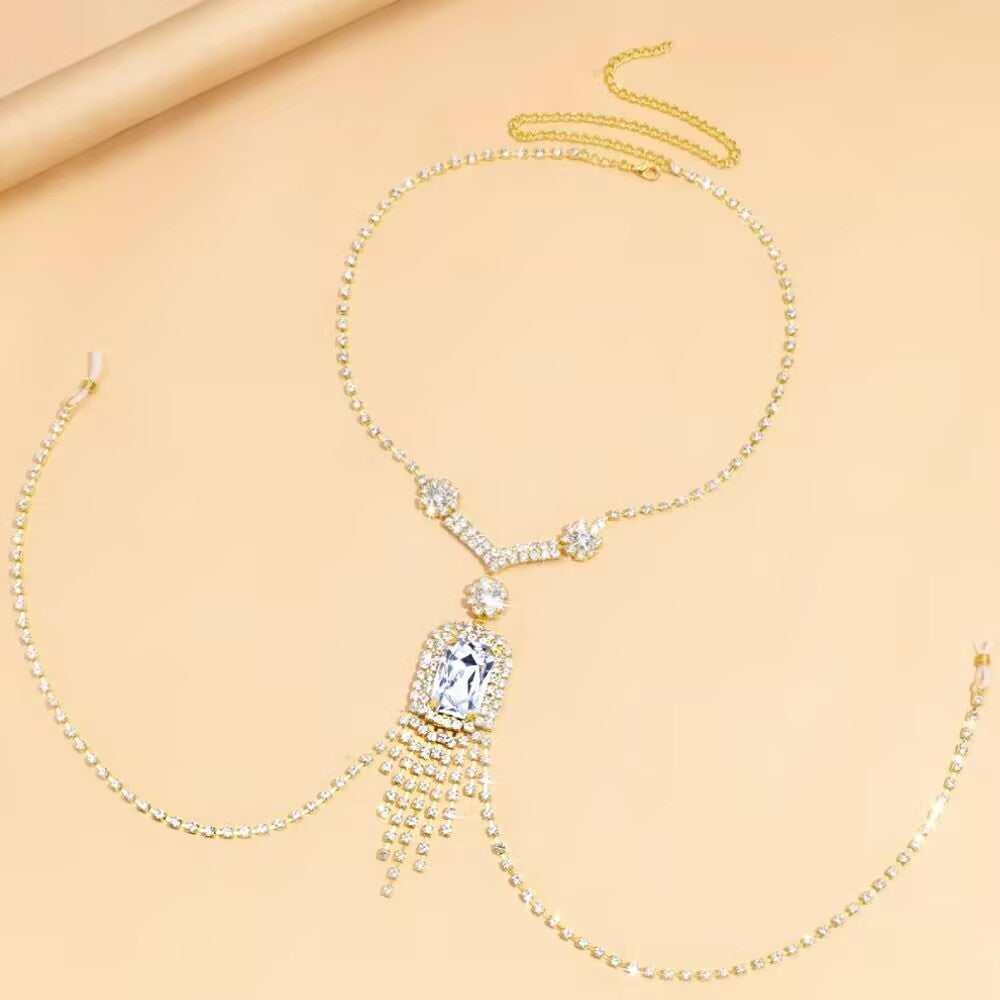 Flatlay view of a luxury gold crystal tassel underbust body chain necklace showcasing adjustable non-piercing loops and a geometric centerpiece stone.