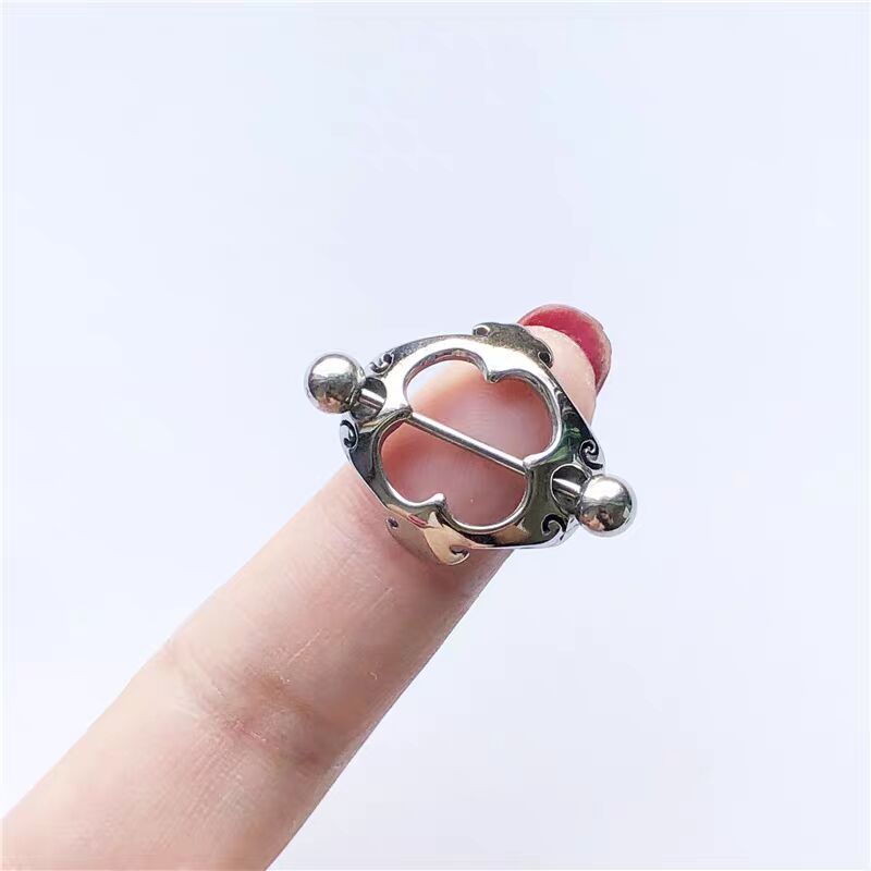 A vintage gothic style nipple shield held on a finger to demonstrate scale and design.
