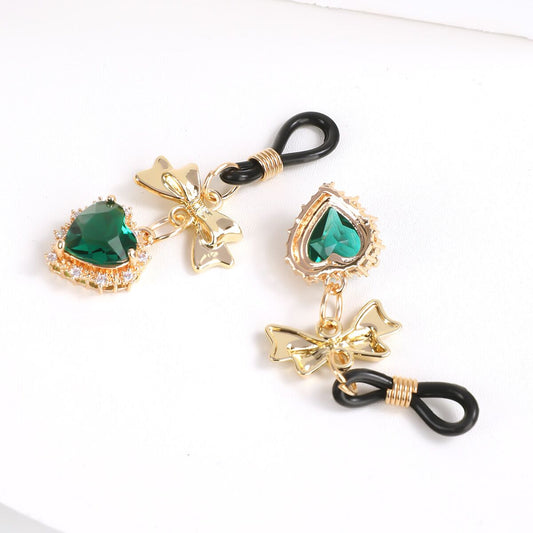 A pair of adjustable non-pierced nipple rings with emerald green hearts on a clean white surface.