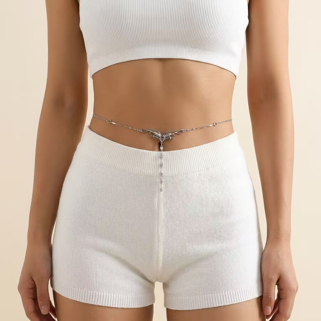 Model wearing a silver flame body chain around her waist styled with white cropped top and shorts