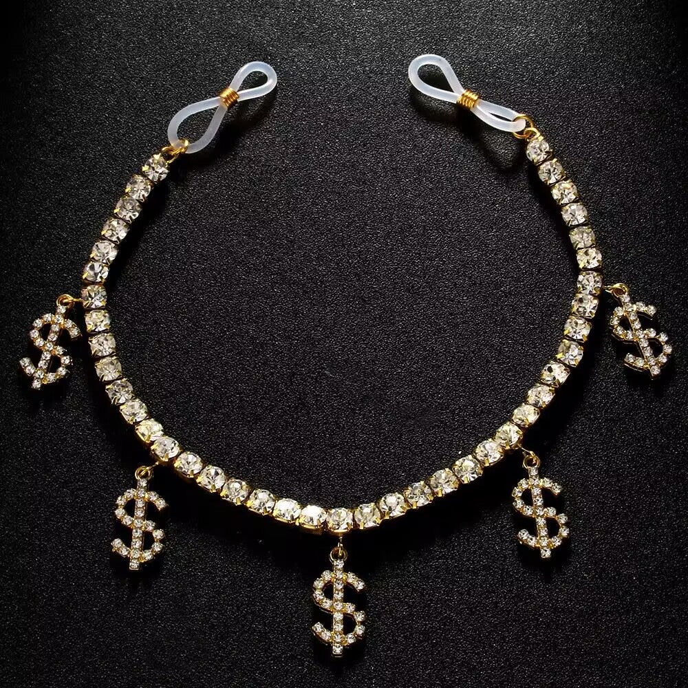 A close-up of a female model wearing a sexy non-piercing rhinestone nipple clasp breast chain with iced-out dollar sign charms dangling over a low-cut dress.