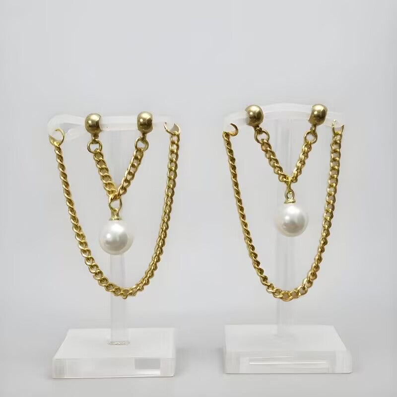 Non-piercing nipple jewelry with white faux pearl pendants and gold dangle chains showcased on clear display stands.