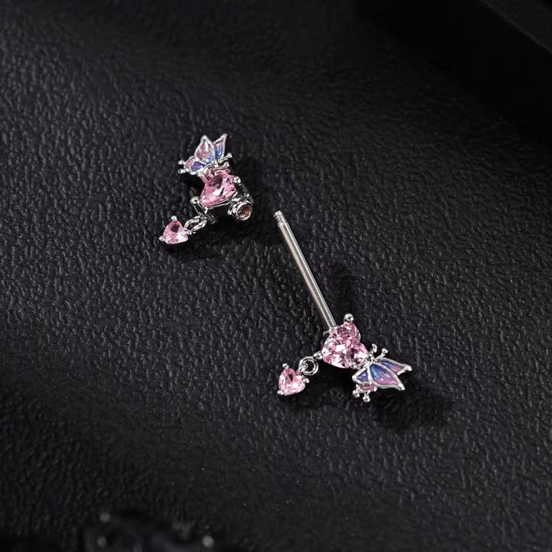 Close-up shot of a detachable pink heart nipple ring on a black leather background, showcasing the removable decorative ends.