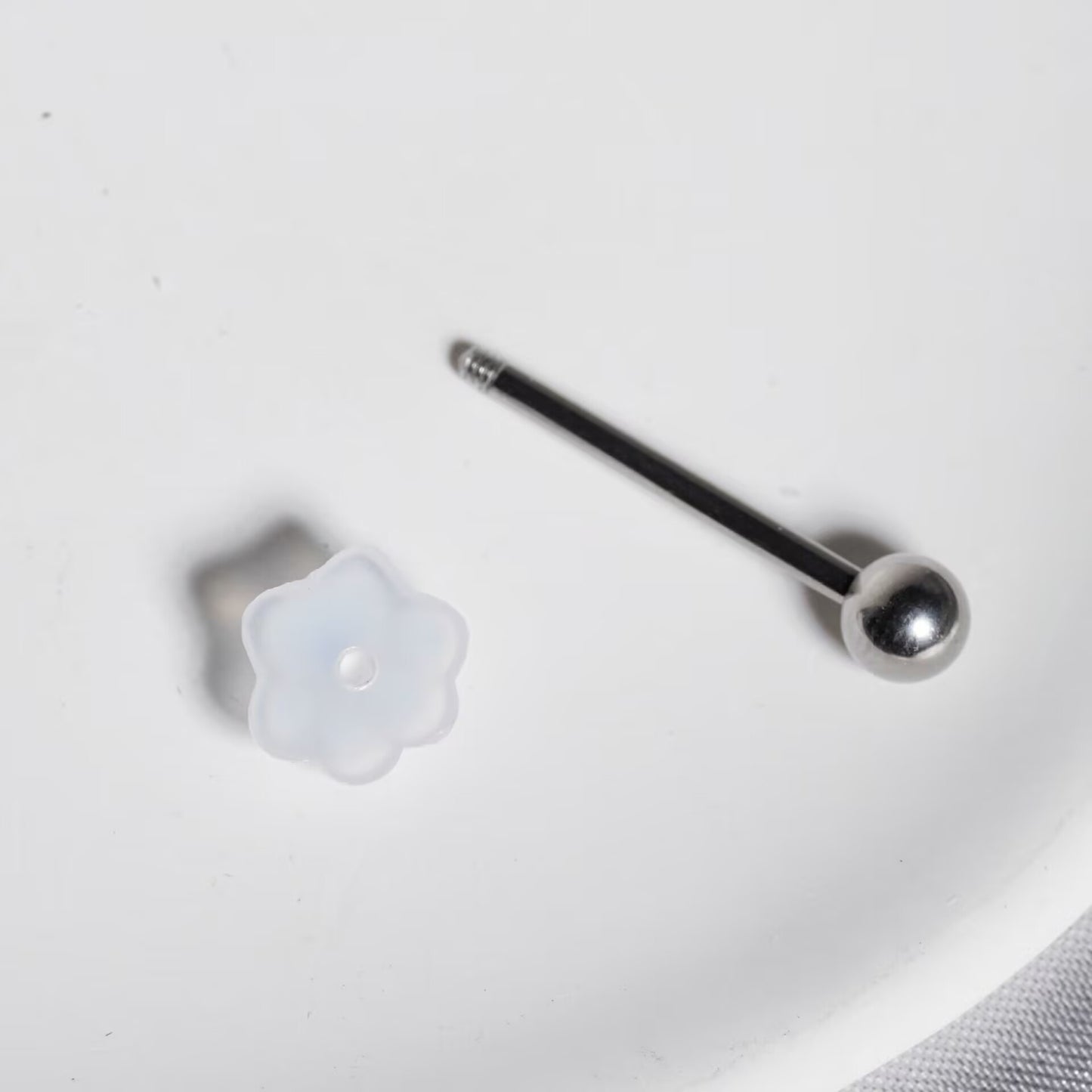 Detached view of resin straight barbell stem with screw ball and translucent resin cat paw top element