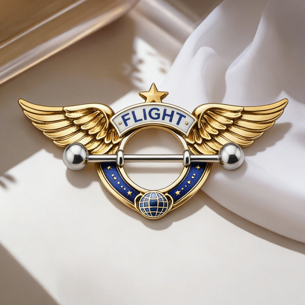 Close-up of a decorative flight-themed nipple shield resting on a soft white fabric.