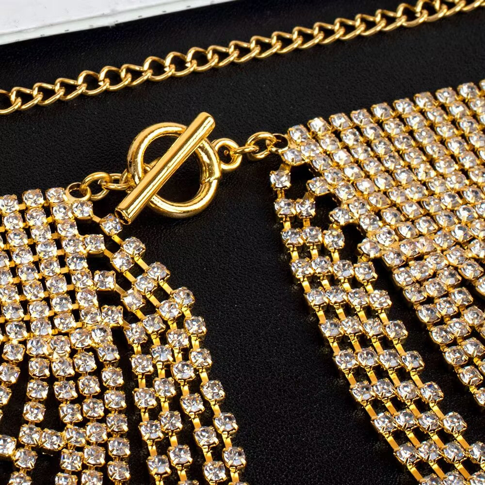 Macro detail view of the gold T-bar toggle clasp closure and rhinestone mesh construction of the chest chain.