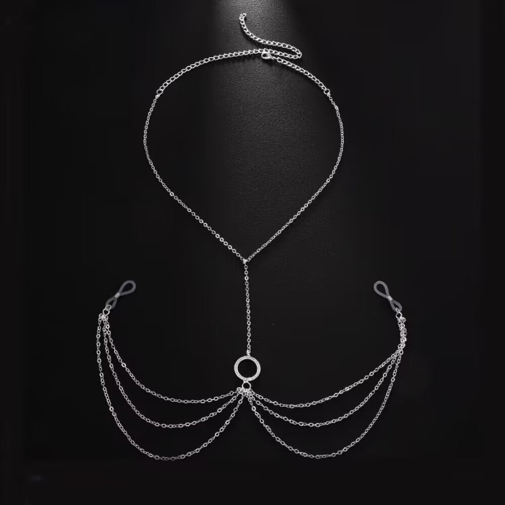 Product display of a silver fake nipple ring necklace and body chain jewelry with adjustable rubber loops and multi-layer chain tassels laid flat against a black background.