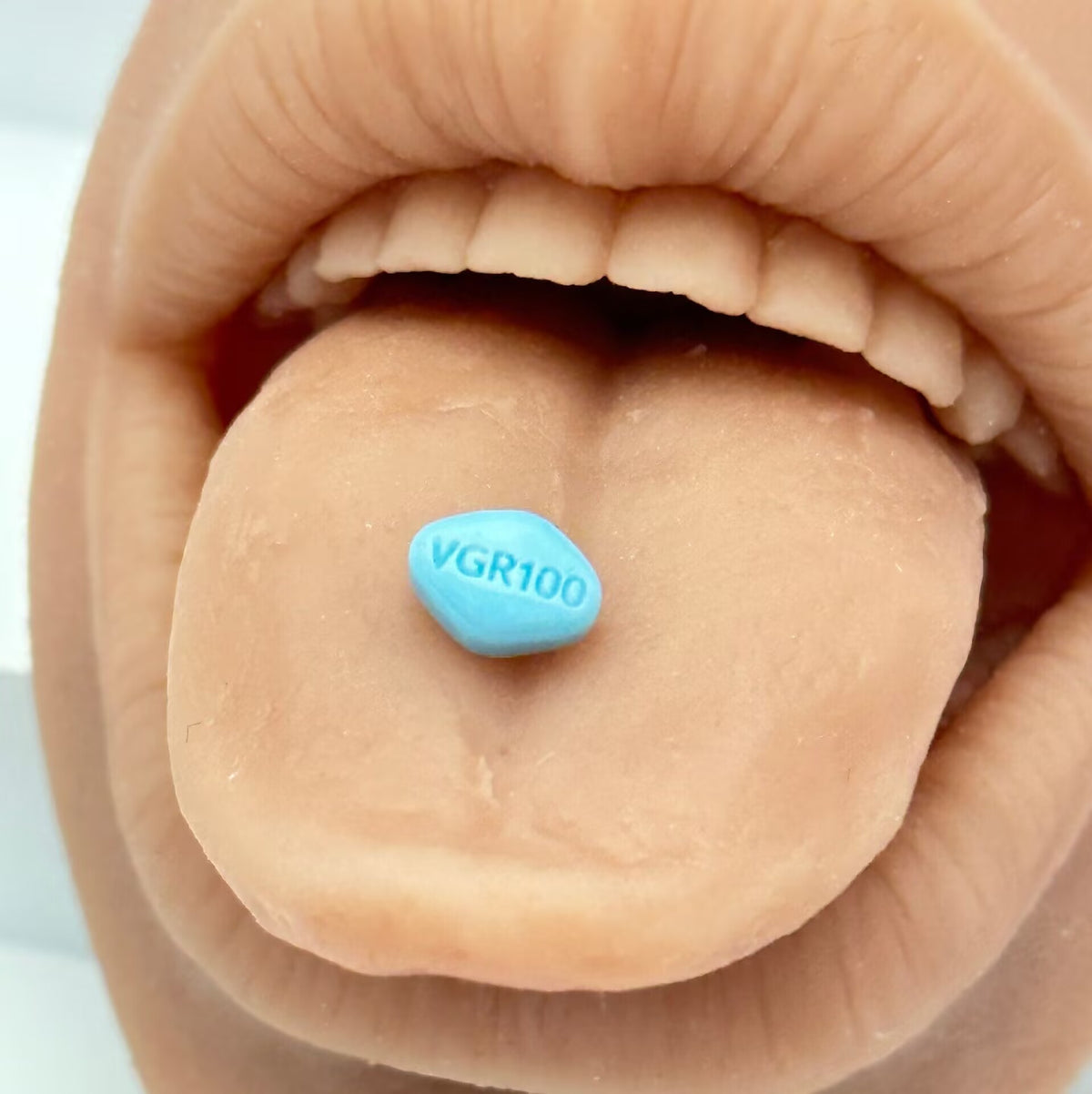 14G tongue barbell with blue pill end modeled on tongue showing VGR100 text side.