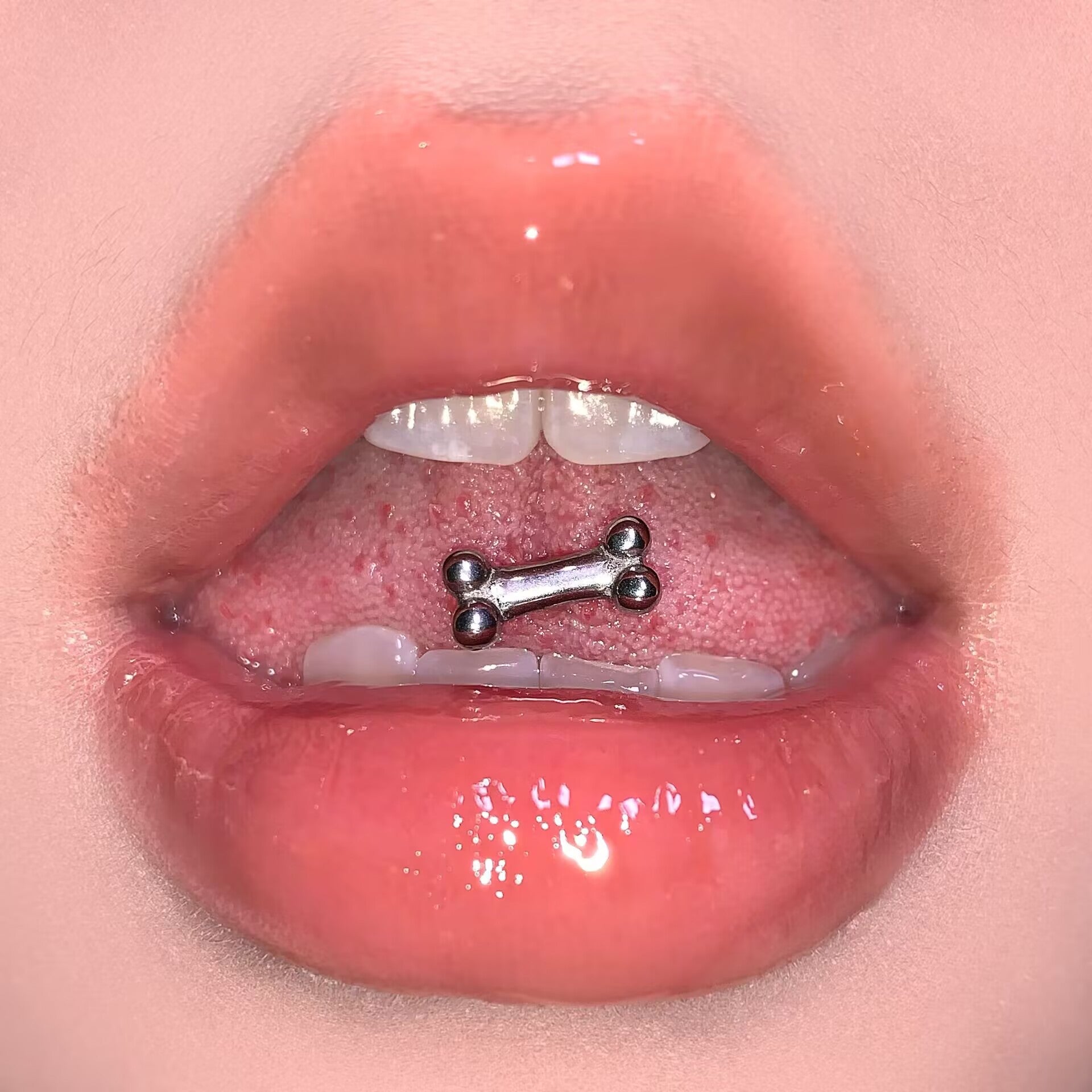 High-polish 316 stainless steel dog bone tongue ring worn on tongue showing flat front fit
