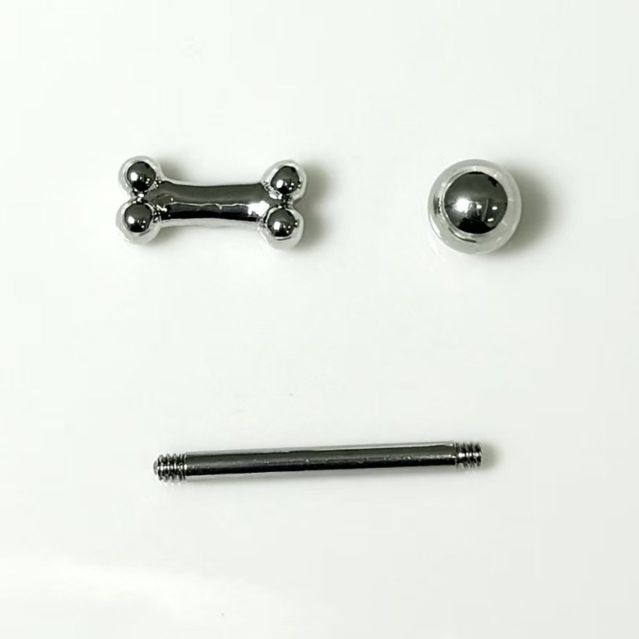 Three-piece disassembly of dog bone tongue ring showing bone top 316 steel straight bar and ball