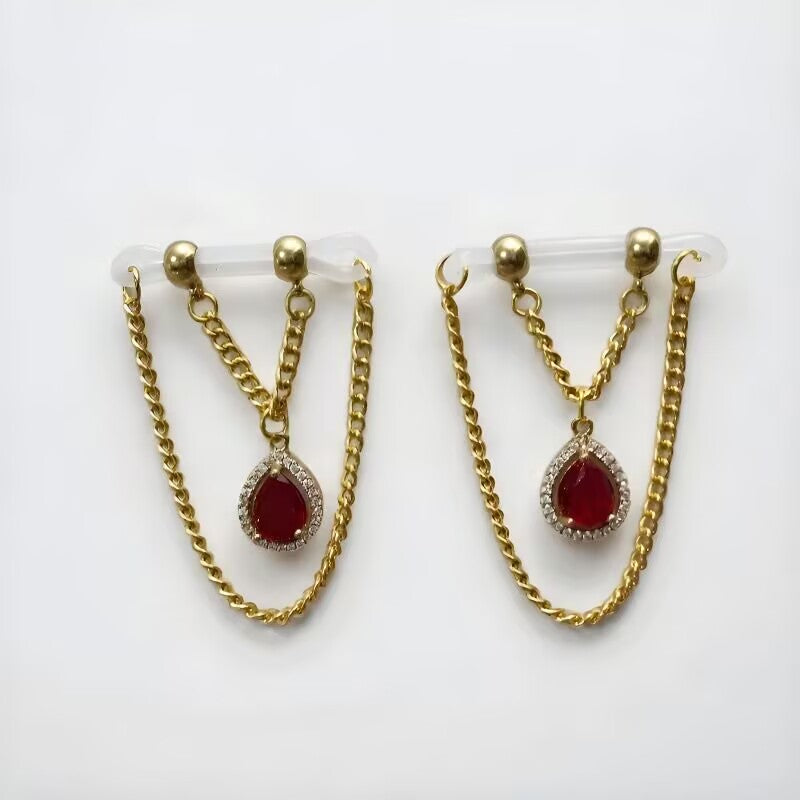 Non-pierced body jewelry featuring bright red heart CZ gems surrounded by cubic zirconia pavé with gold drop chains on clear bands.