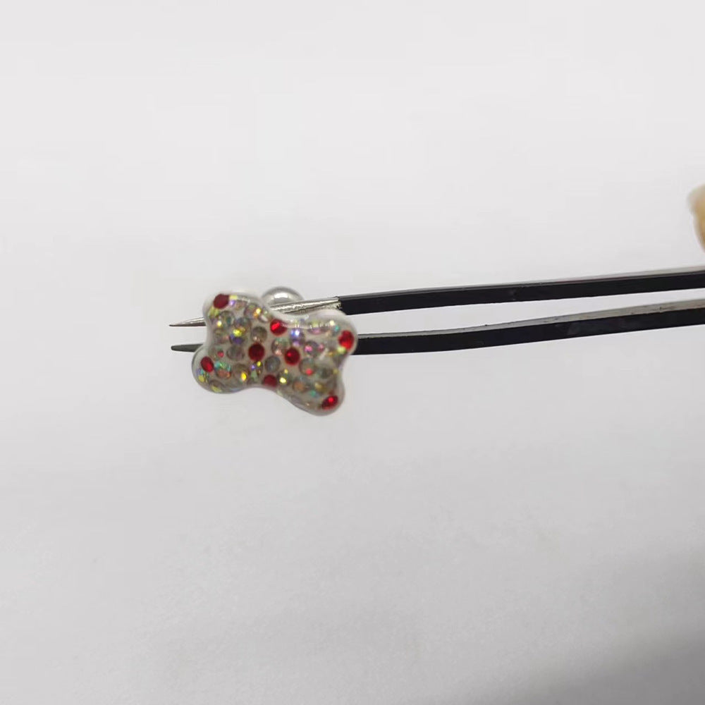 One AB White butterfly tongue barbell held with tweezers, showing iridescent rhinestones with red accents.