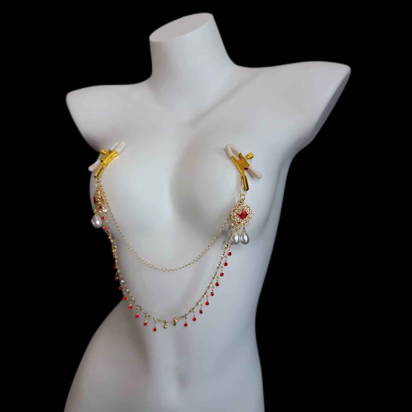 Adjustable gold-tone screw clamp breast chain accessory with ruby filigree accents, connecting chain, and dangling drop pearls.
