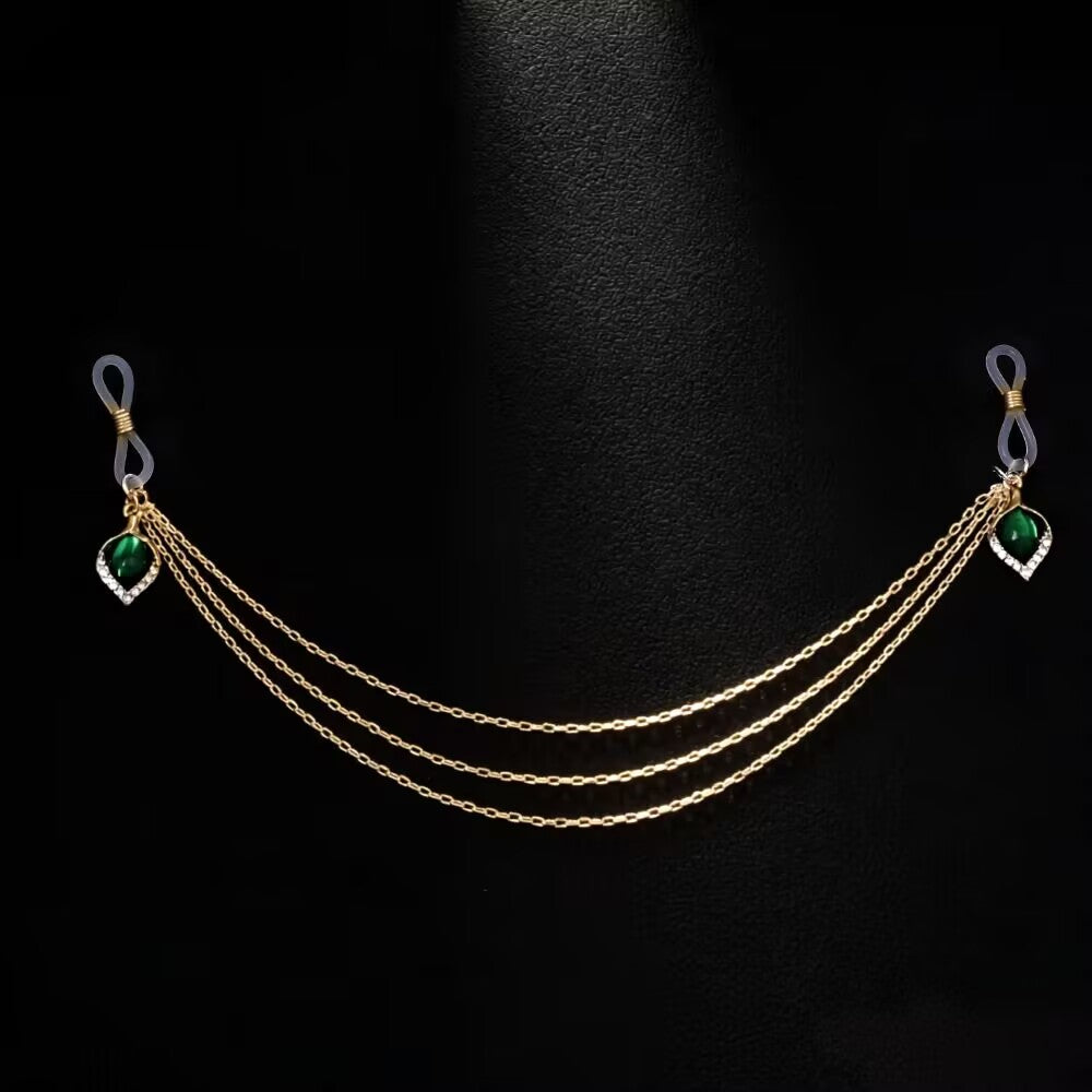 Product display of a gold connected fake nipple piercing jewelry chain featuring three-layered chains and vintage green teardrop gems on a black background.