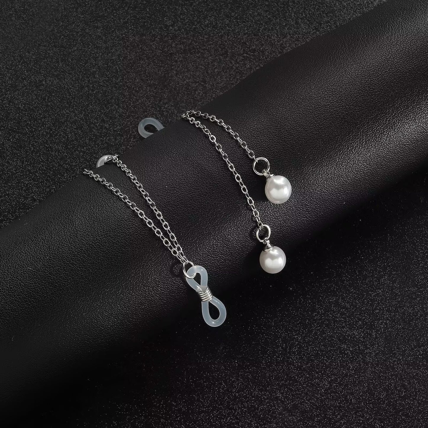 Close up view of adjustable silicone loop slider bead and delicate silver chain with faux pearl dangles.