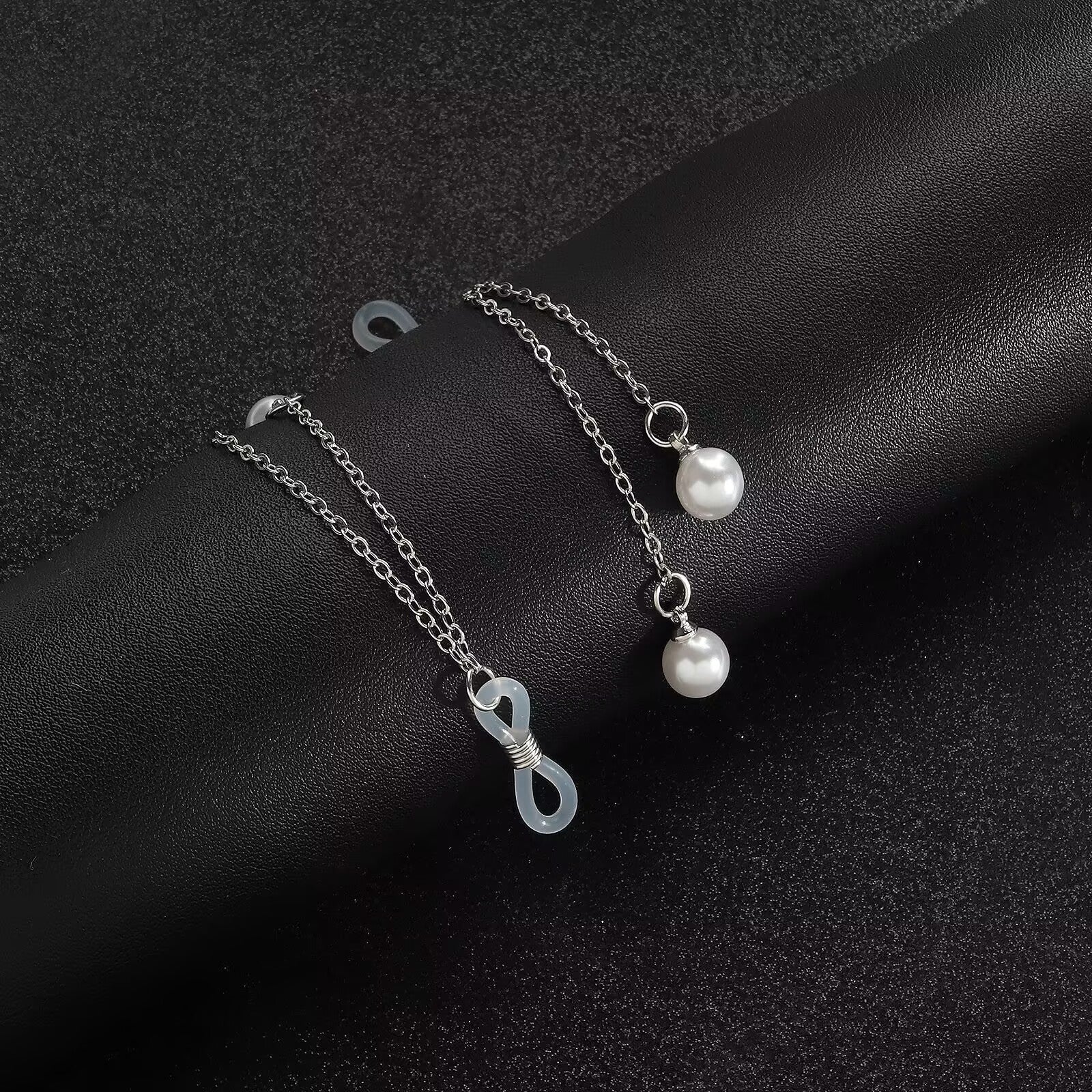 Close up view of adjustable silicone loop slider bead and delicate silver chain with faux pearl dangles.