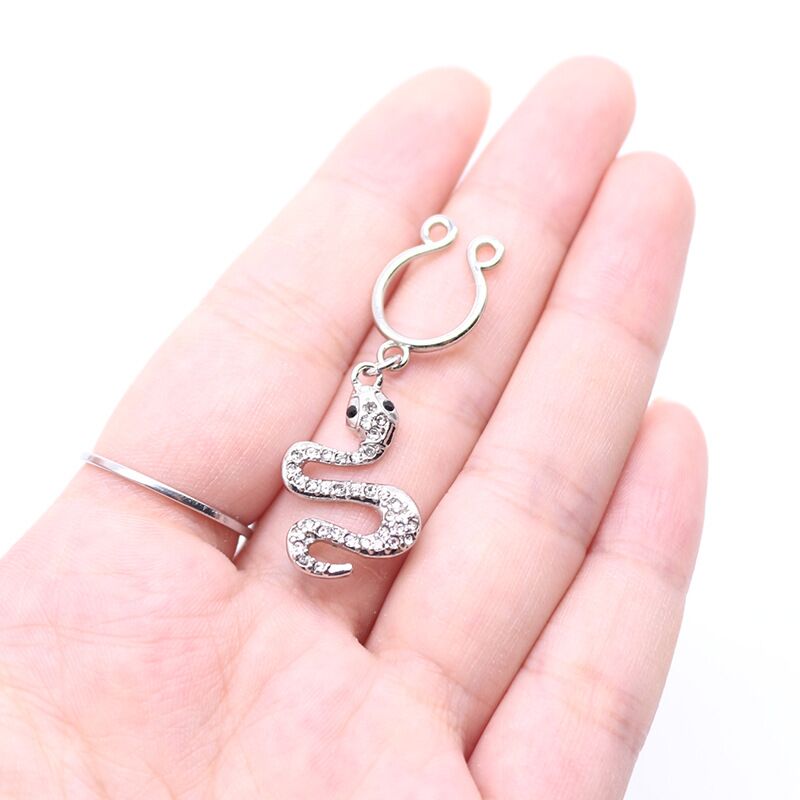 Hand holding a sparkling serpent-themed adjustable nipple clip to show real-life scale and shine.