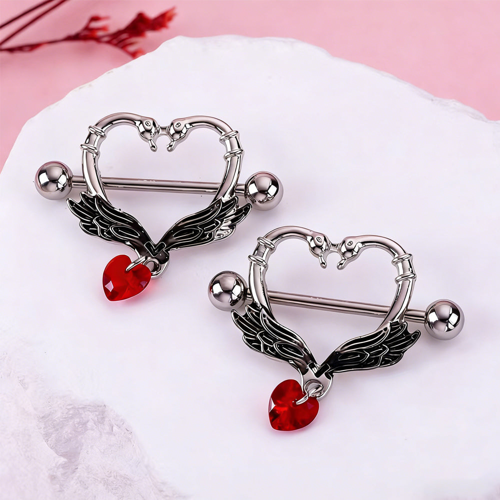 Two swan wing nipple rings displayed on a white textured stone for aesthetic styling.