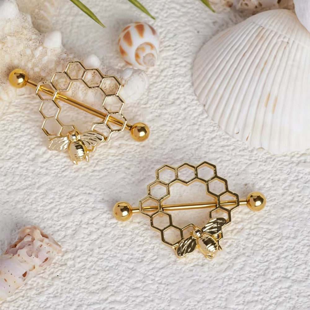 Two honeycomb bee nipple shields arranged creatively with seashells and beach-themed decor.