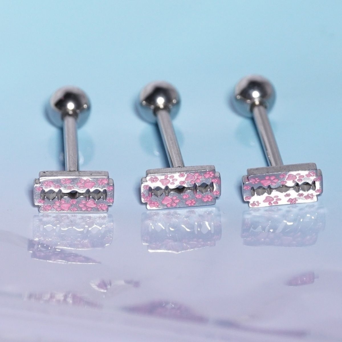Close up of pink paw print razor blade tops on straight tongue barbells