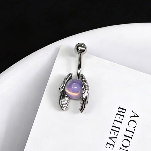 Angel wings belly button ring with a glowing purple opalite stone resting on a white card