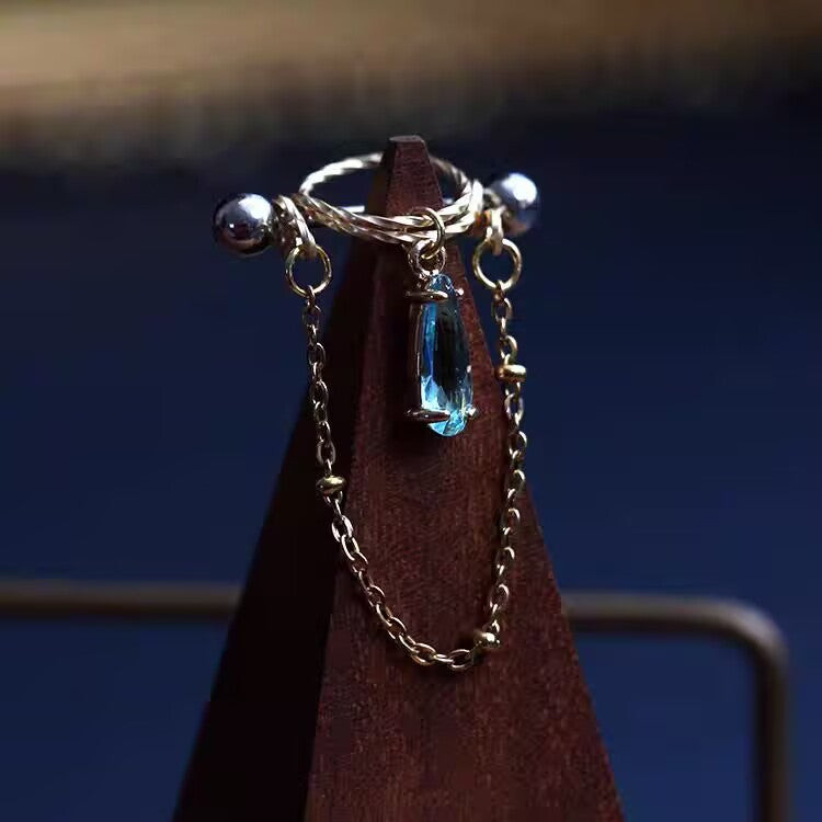 Aqua ocean blue waterdrop cubic zirconia nipple ring featuring a twisted halo shield and dangle chain.