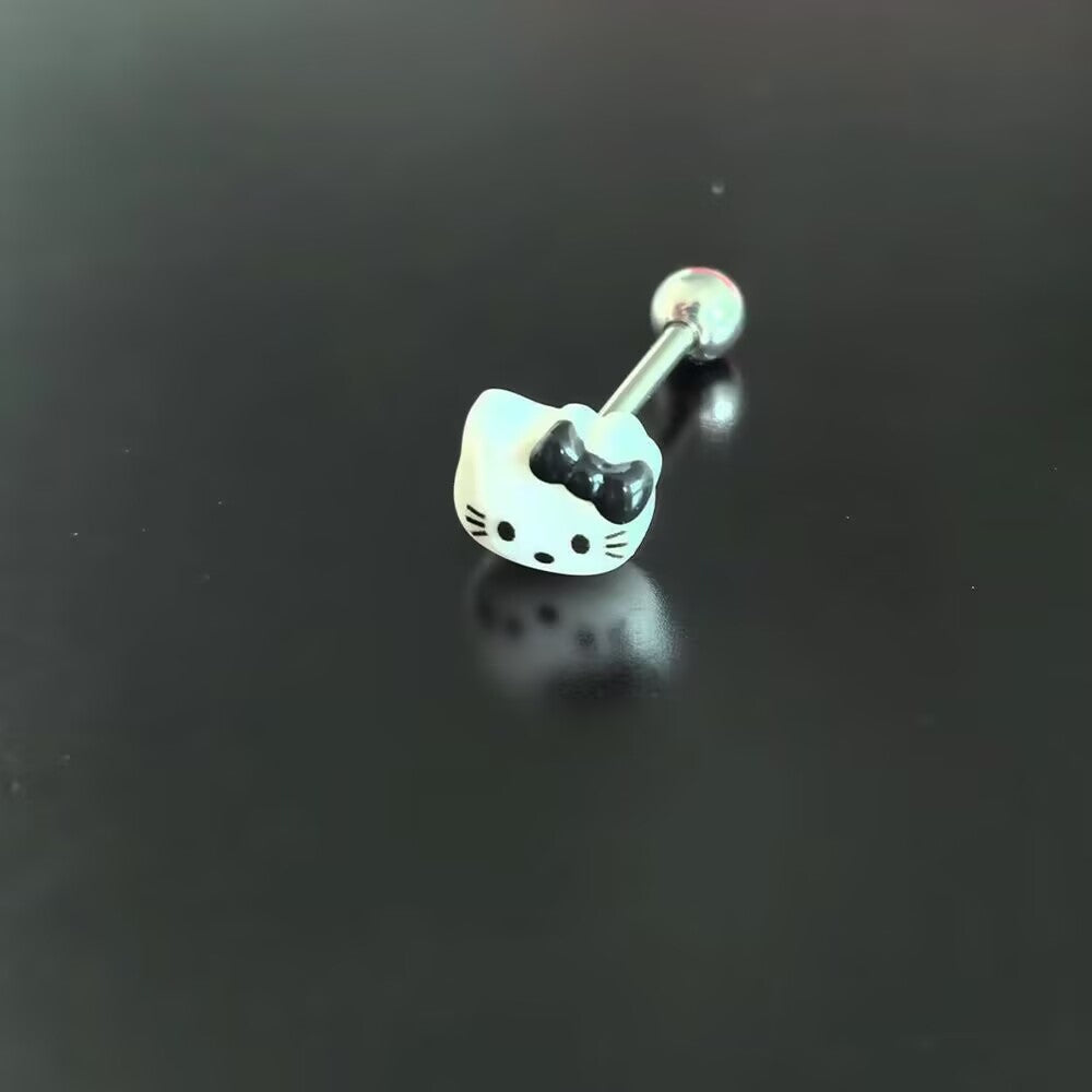 Close up view of 14G cute white kitty tongue ring with black bow top on dark background.