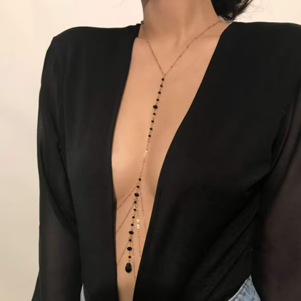 Teardrop pendant body chain necklace resting on chest with a deep V-neck top.