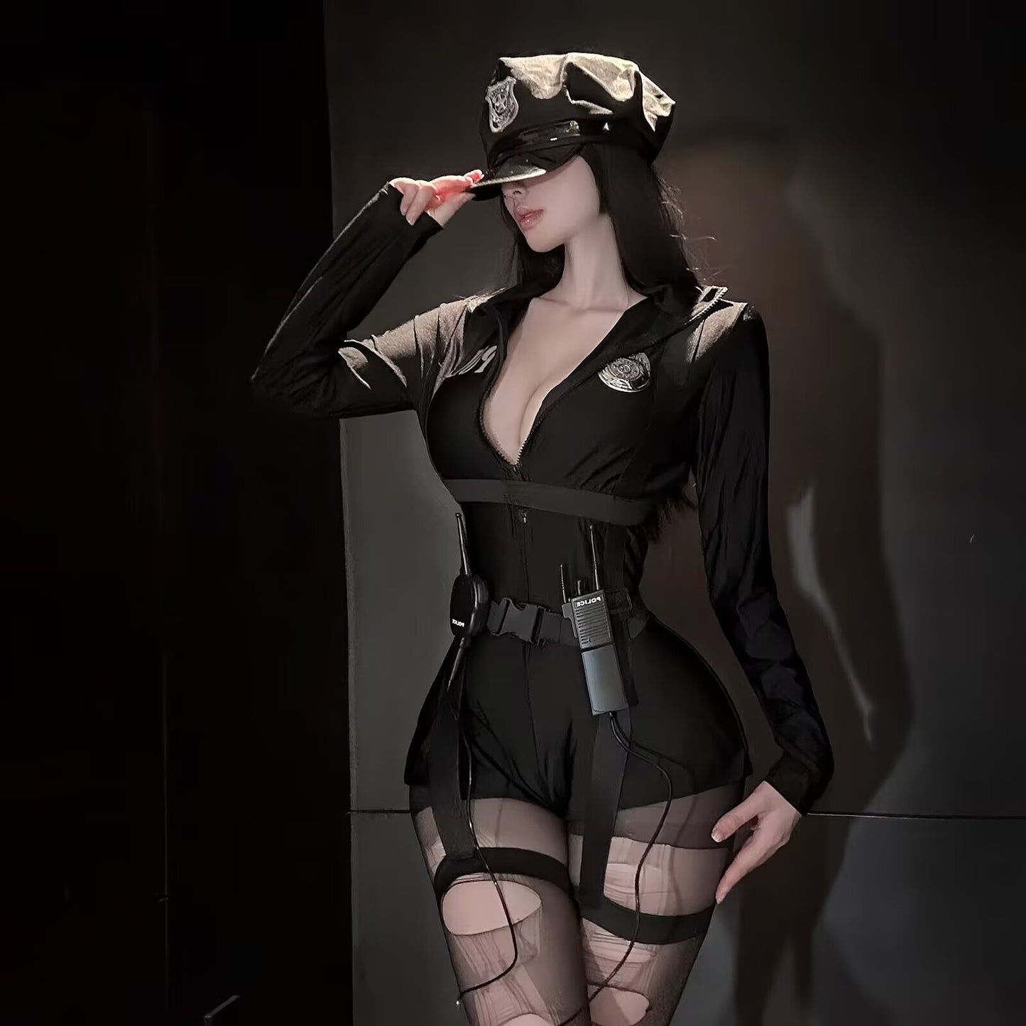 Studio portrait of a woman in a sleek onyx black E-girl style cop costume featuring a deep V zipper bodysuit and tactical leg straps.