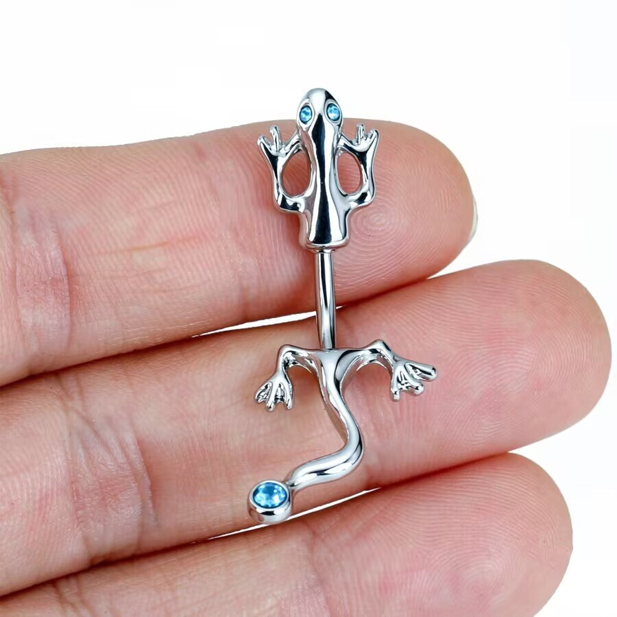 Handheld close-up shot highlighting the glossy polish and aqua blue crystal accents of the gecko navel barbell.