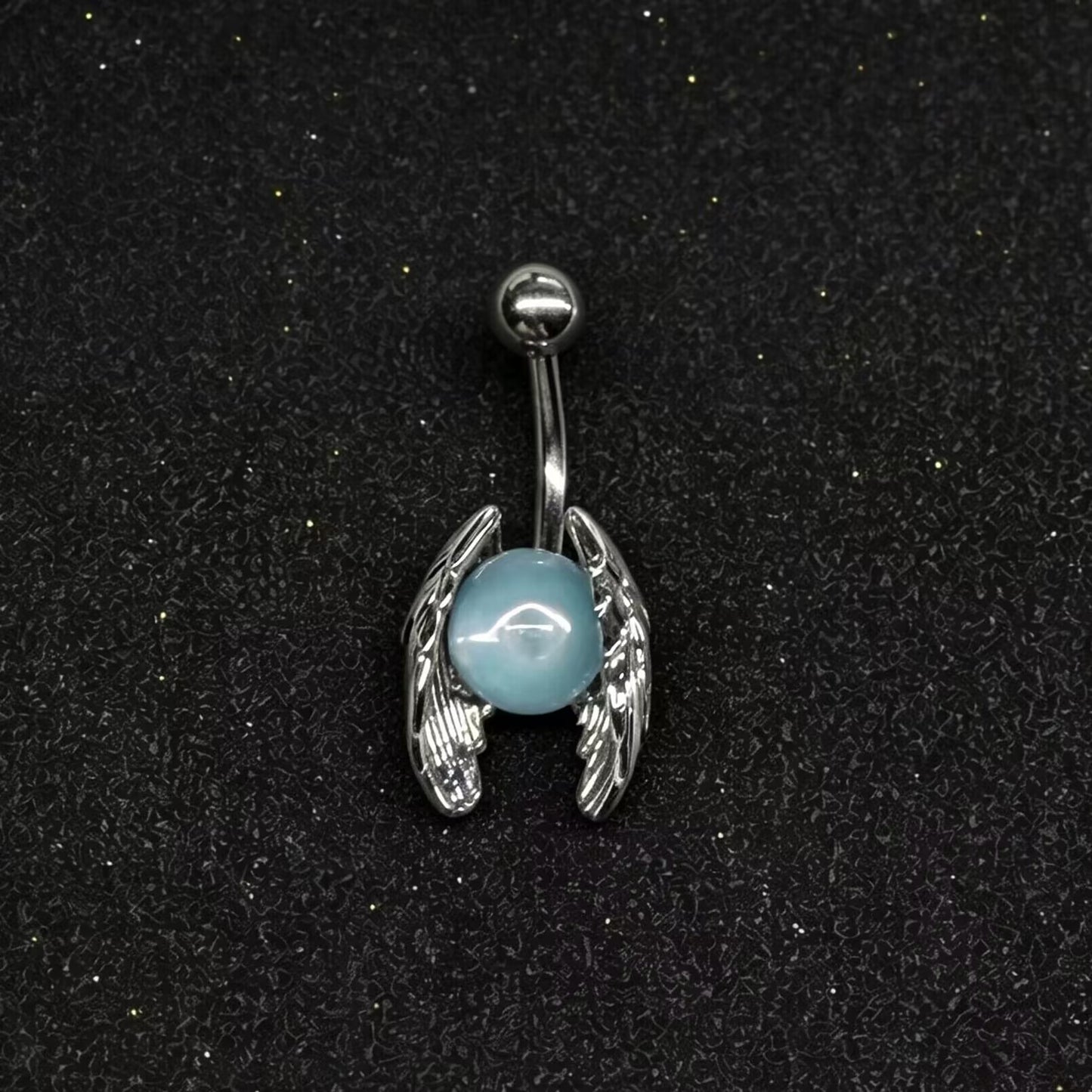 Angel wings belly button jewelry holding a dreamy pastel blue opal stone on a black glitter background