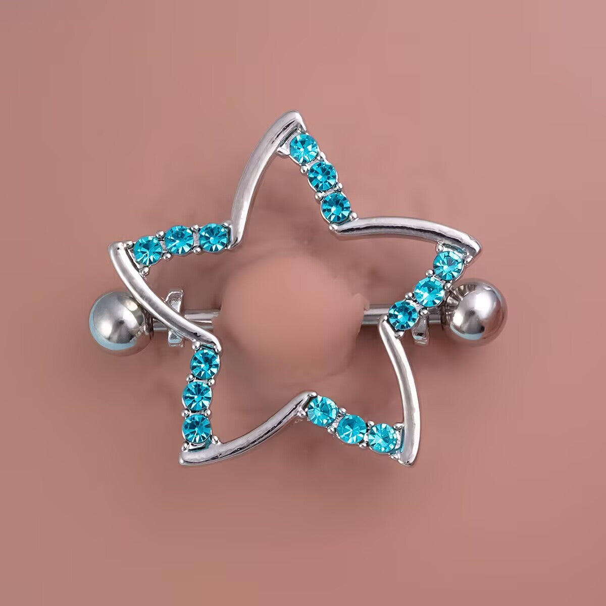 Close-up of a blue crystal star nipple shield fitted on a professional silicone piercing model.