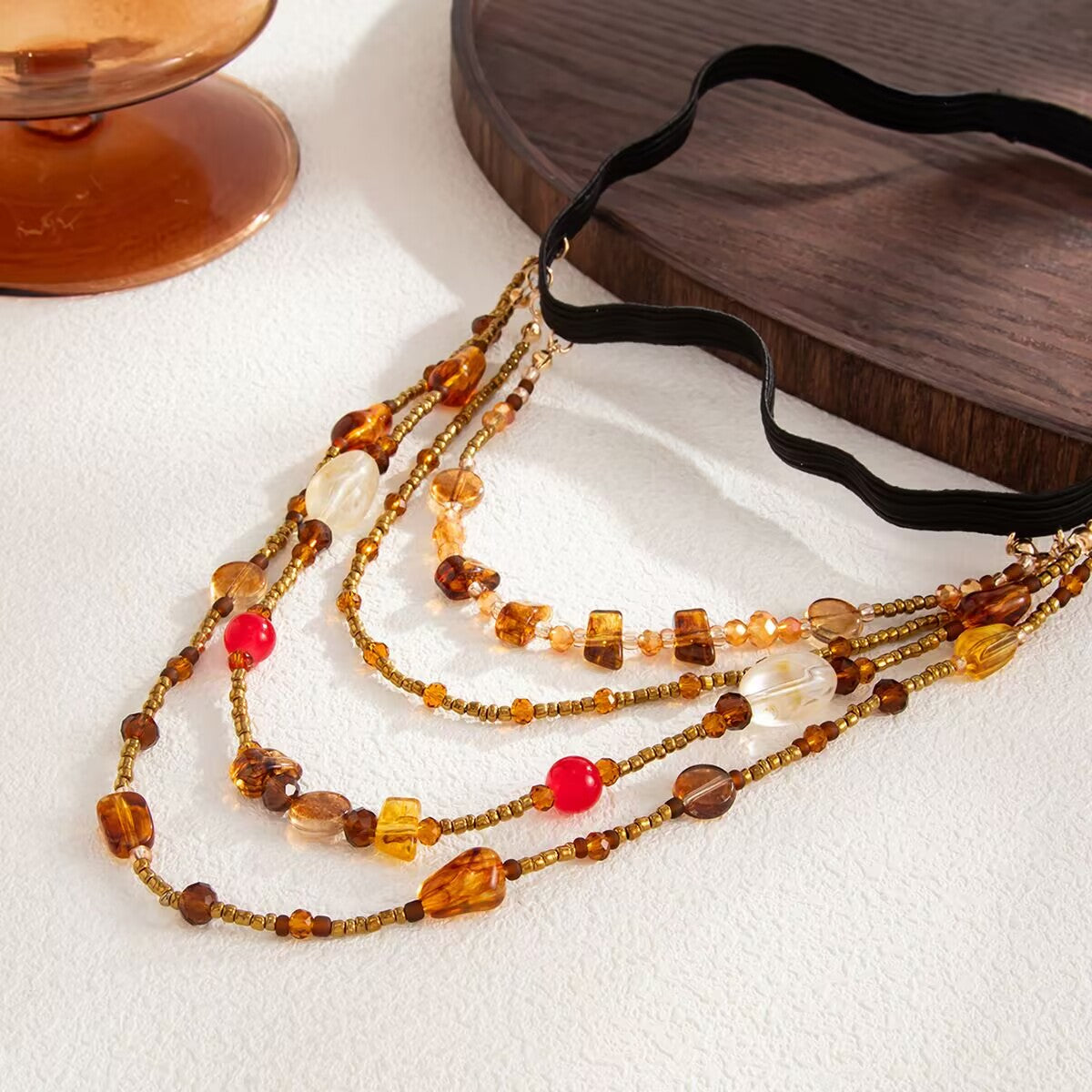 Close-up view of bohemian amber and red crystal beads on a layered leg body chain jewelry piece.
