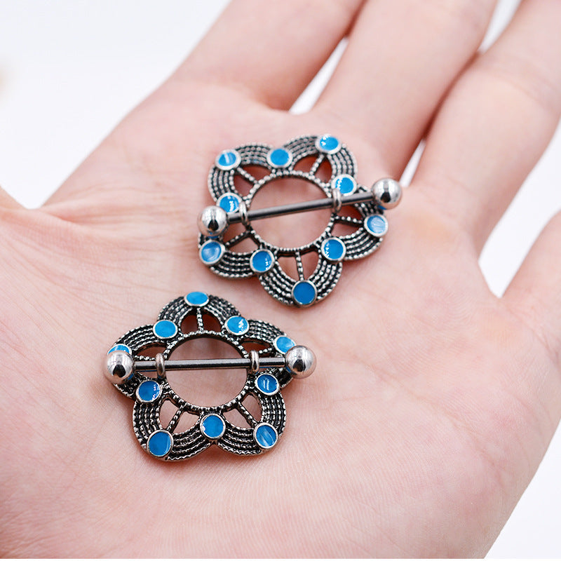 A pair of vintage bohemian nipple shields held in a hand to show the actual size and scale of the jewelry.