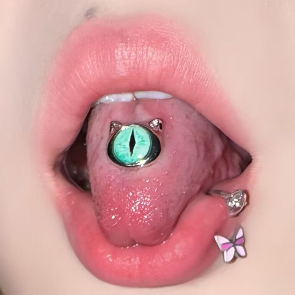 On-body presentation showing a green cat eye tongue ring barbell worn in a center tongue piercing.