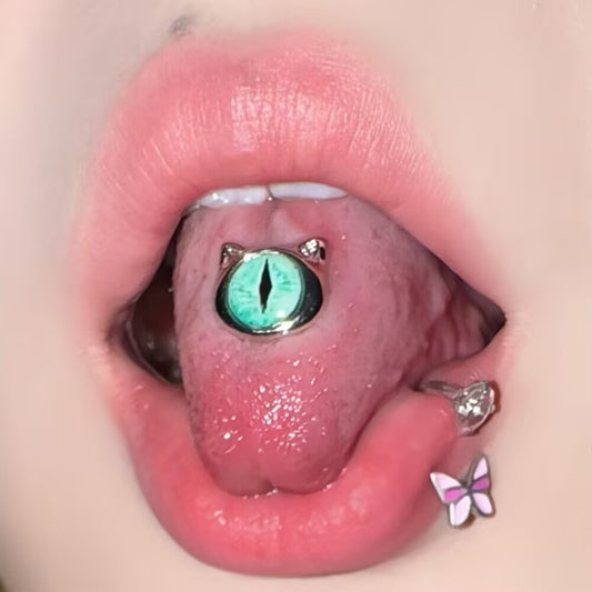 On-body presentation showing a green cat eye tongue ring barbell worn in a center tongue piercing.