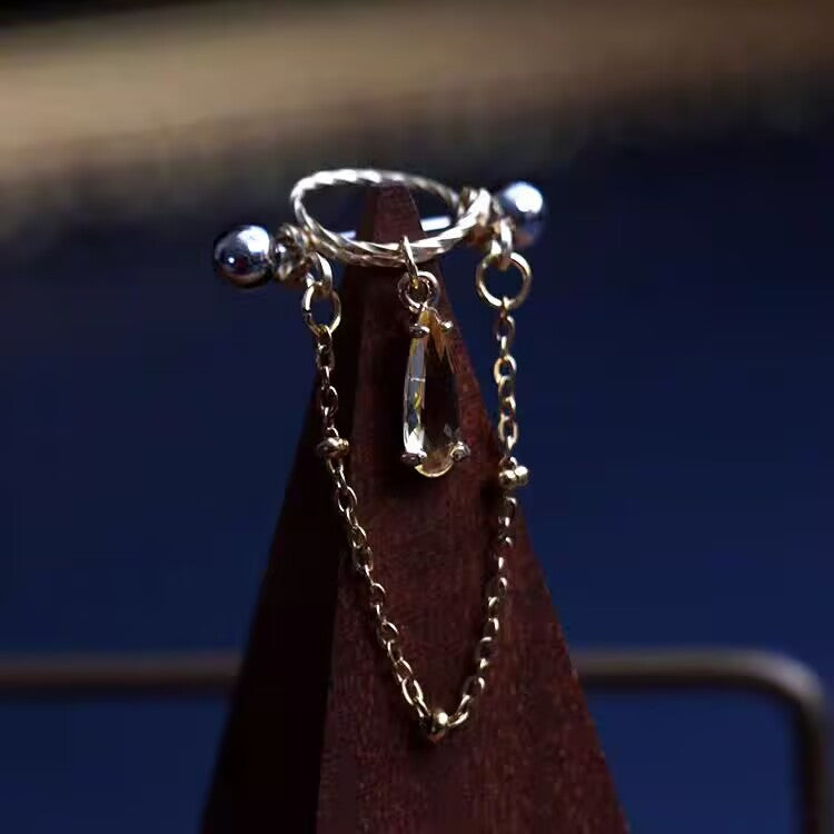 Champagne yellow waterdrop CZ nipple shield jewelry with dangling chain mounted on wooden cone.