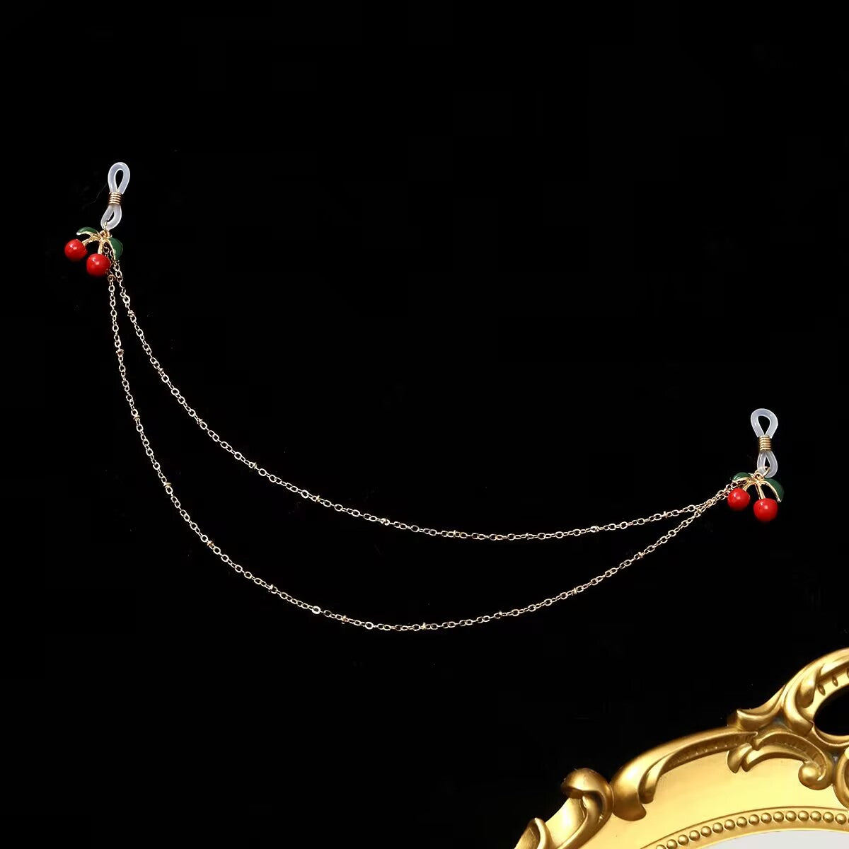 Cherry fake nipple ring chain with clear silicone loops laid flat against a black background