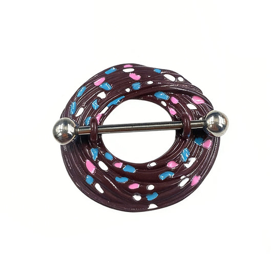 Close-up view of a single chocolate-themed donut nipple ring featuring blue, pink, and white sprinkles.