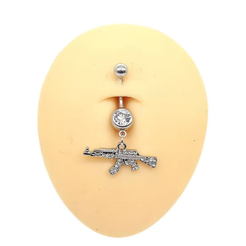 Classic clear crystal pave AK47 gun dangling navel piercing shown on a silicone belly display model.