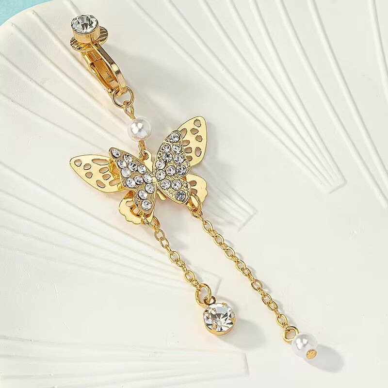 Close up view of clip on fake belly button ring featuring crystal paved butterfly and tassel details