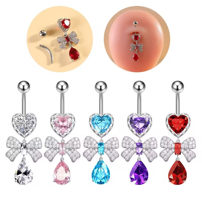 Five color variations of a dangling belly button ring featuring a crystal heart, sparkling bowknot, and teardrop charm, shown flat and on a piercing model.